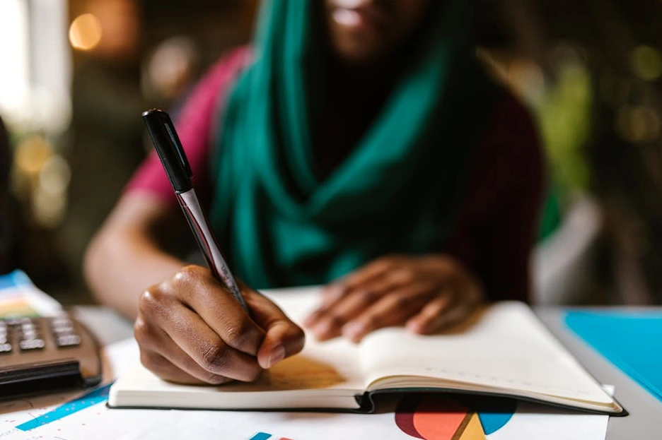 Persona che scrive su un taccuino in un ambiente luminoso